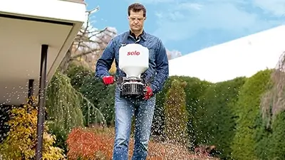 Mann mit Gerät zum Verteilen von Dünger